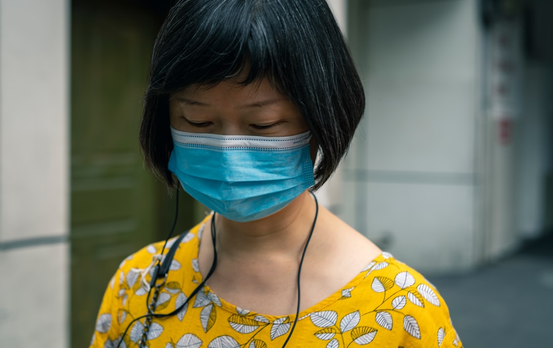 woman in yellow and white floral shirt with blue face mask