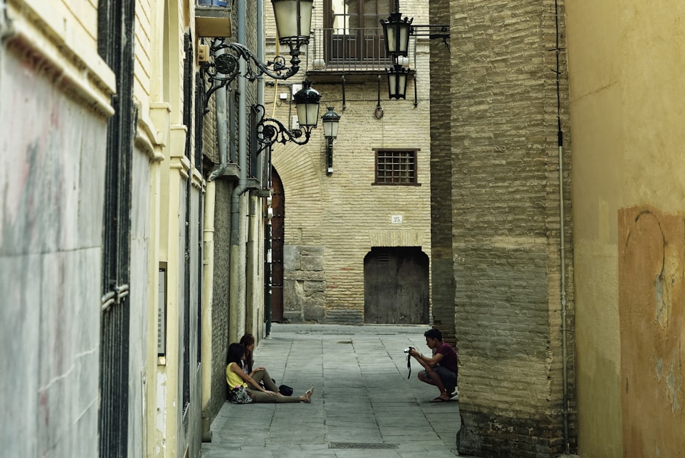 man in black jacket sitting on sidewalk during daytime