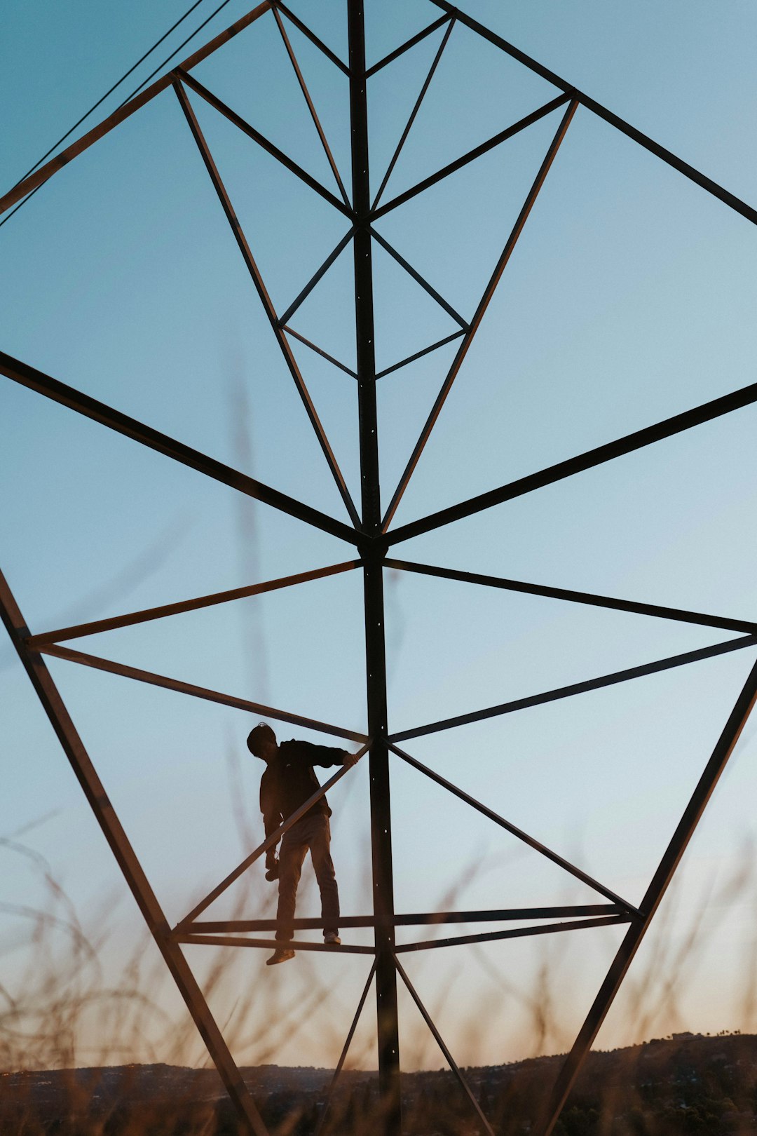 low angle photography of man in red shirt and black pants standing on black metal frame