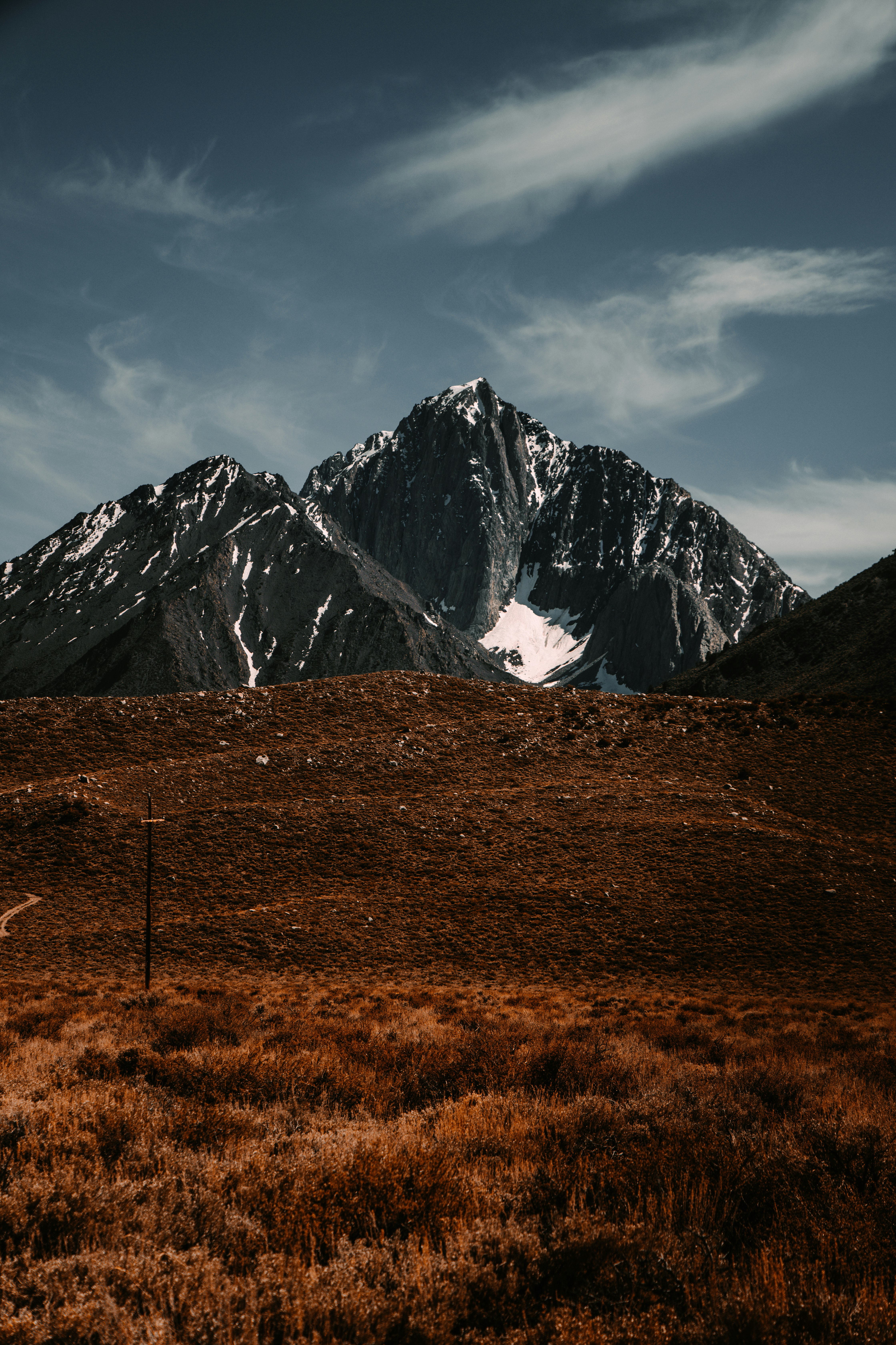 brown grass field near snow covered mountain during daytime