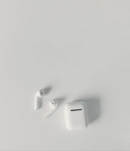 Pair of modern wireless earbuds resting on a minimalist white surface.