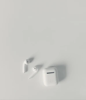 Sleek wireless earbuds resting on a minimalist white surface with soft natural light.