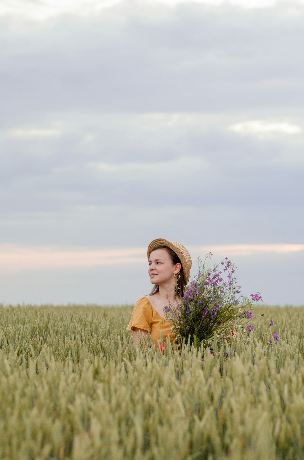 woman in brown sun hat standing on green grass field during daytime