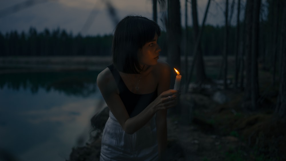 woman in black tank top holding lighted candle