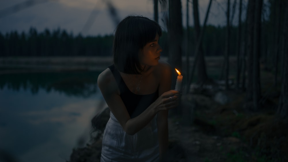 Mujer en camiseta sin mangas negra sosteniendo una vela encendida