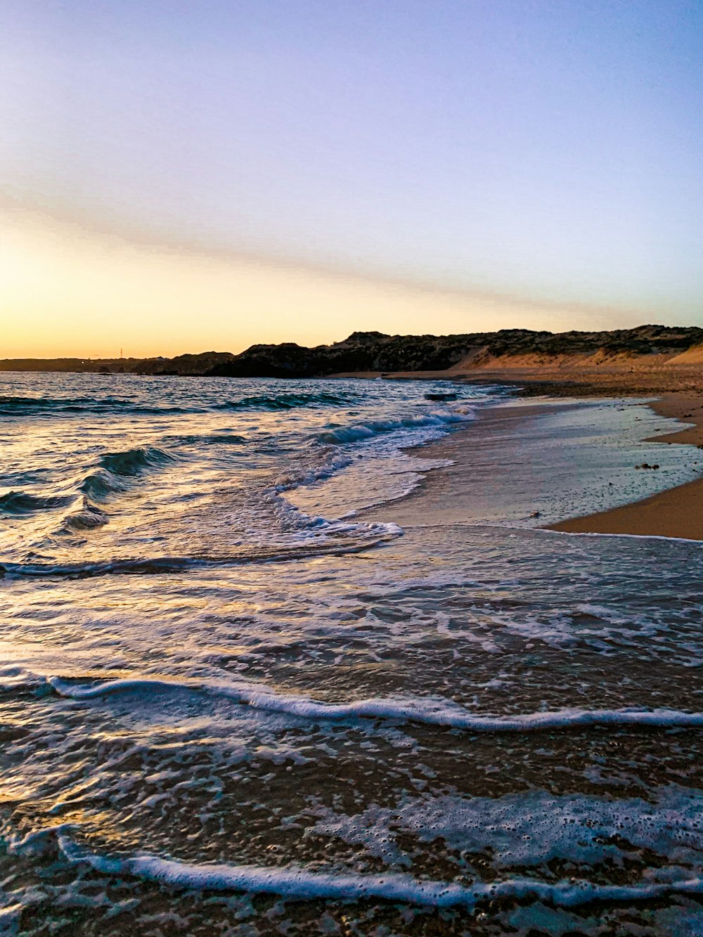 ondas do oceano batendo na costa durante o pôr do sol