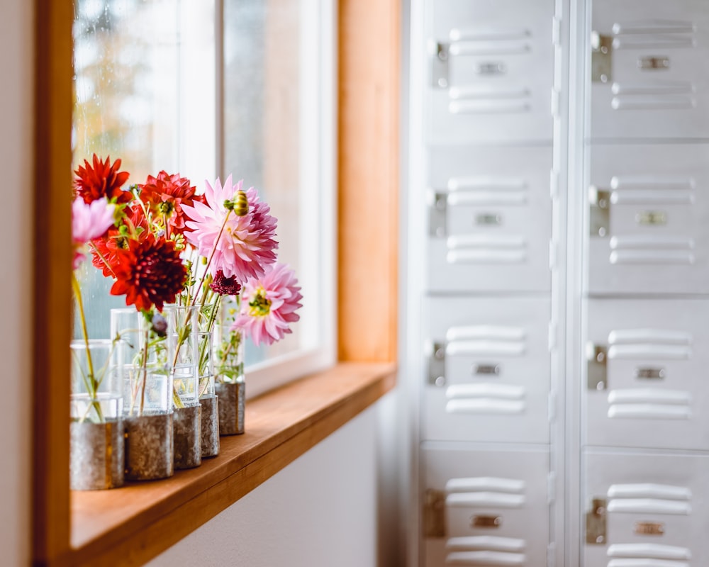 Fleurs roses dans un vase en verre transparent sur une table en bois marron