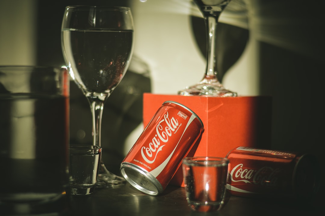 coca cola can beside clear wine glass