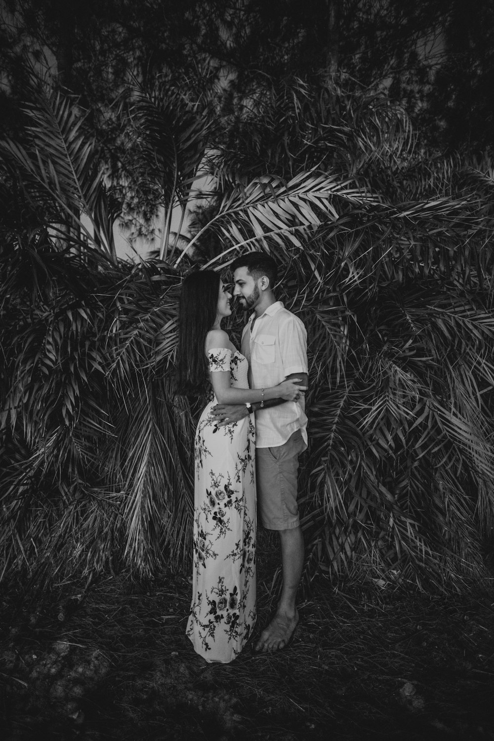 Mujer en vestido blanco de pie cerca de la palmera