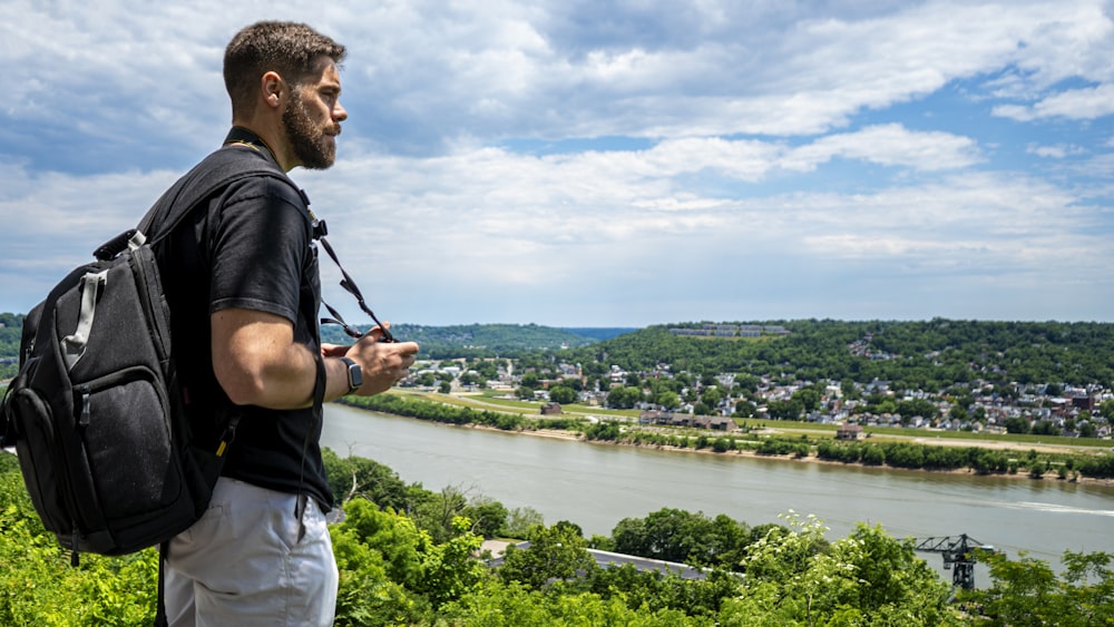 man in black t-shirt standing on rock looking at the city during daytime