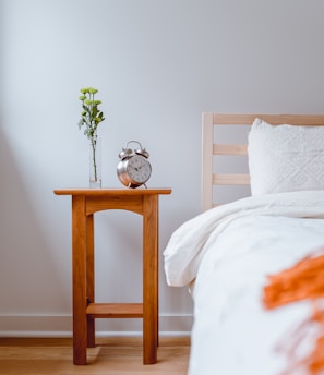 brown wooden table with white and orange floral bed linen