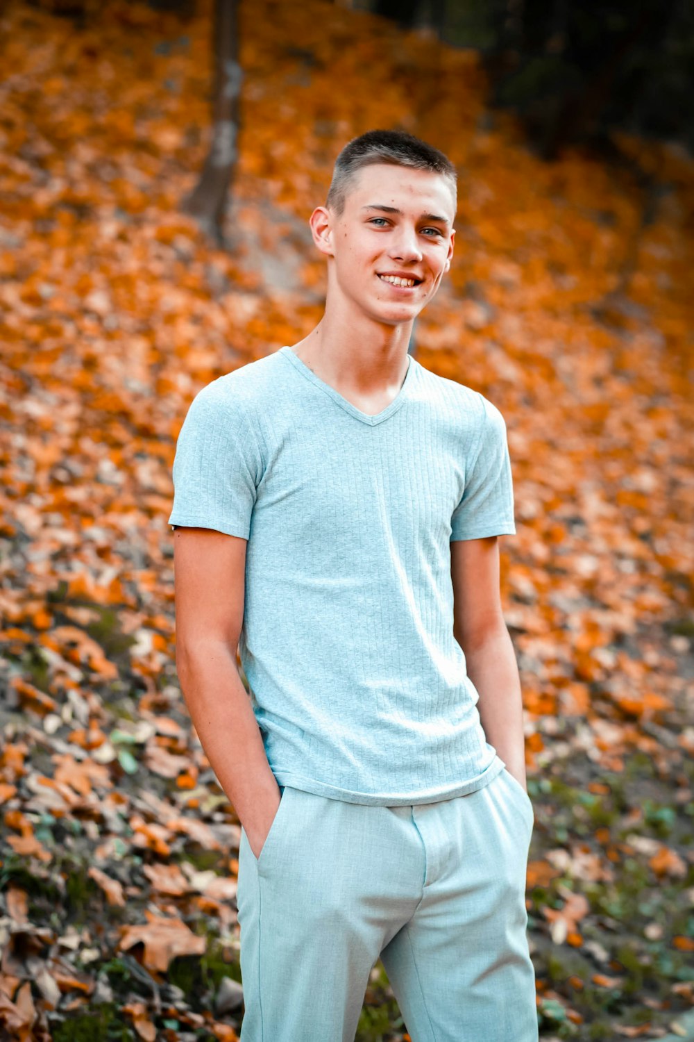 man in white crew neck t-shirt standing on dried leaves