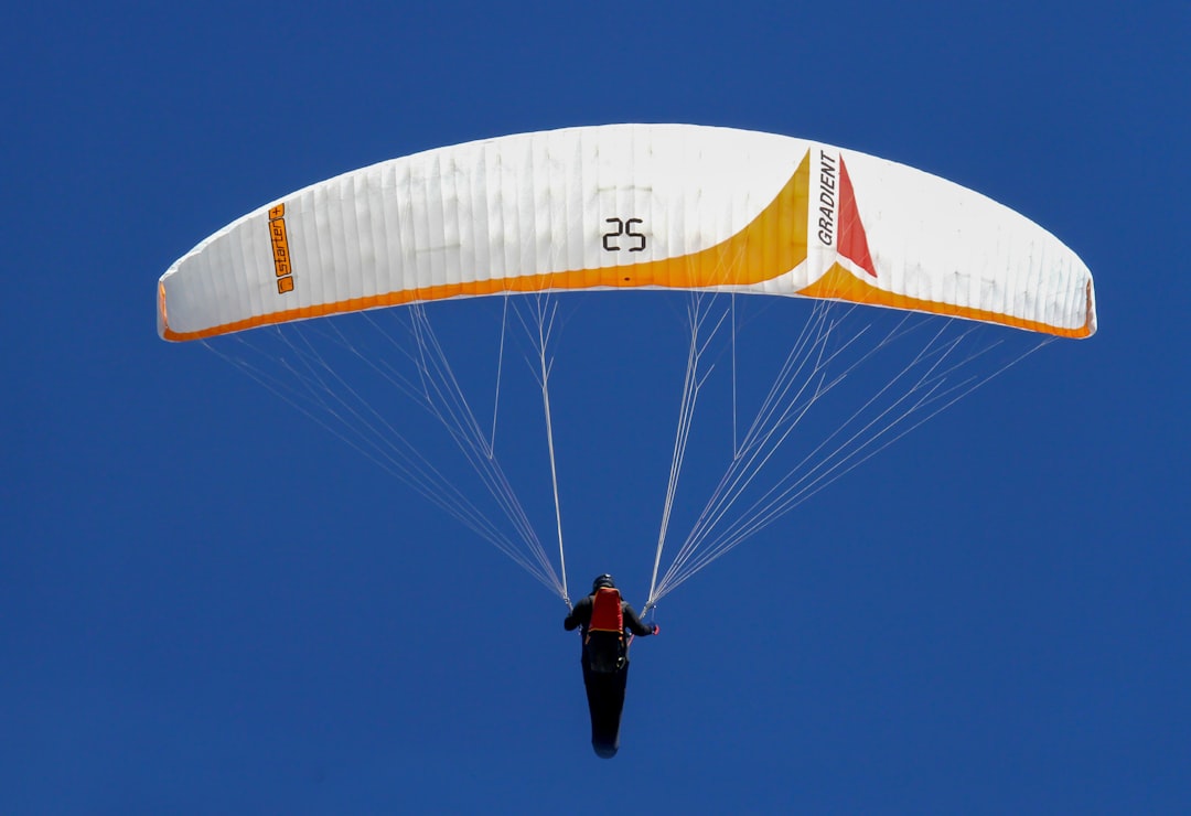 man in black jacket and black pants riding yellow and white parachute