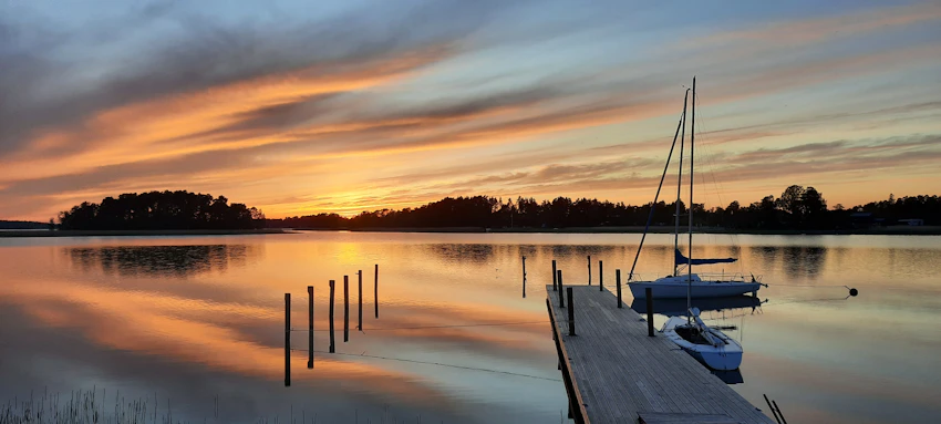 Wooden pier and boats at sunset in Naantali