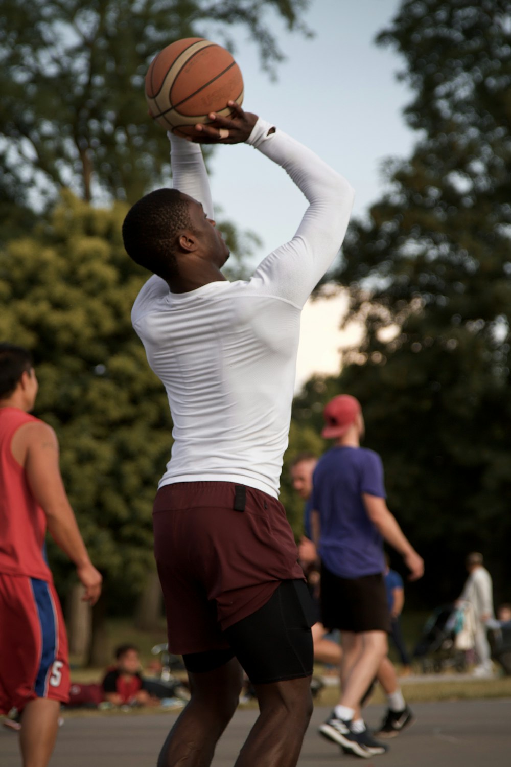 man in white long sleeve shirt and red shorts holding brown ball