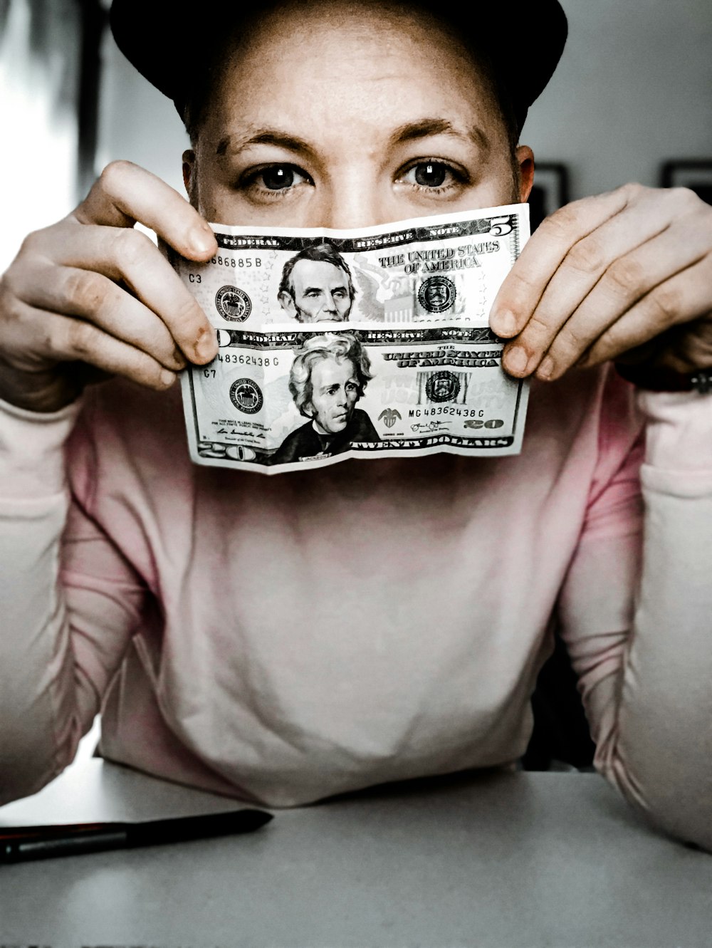 man in pink long sleeve shirt holding 20 us dollar bill