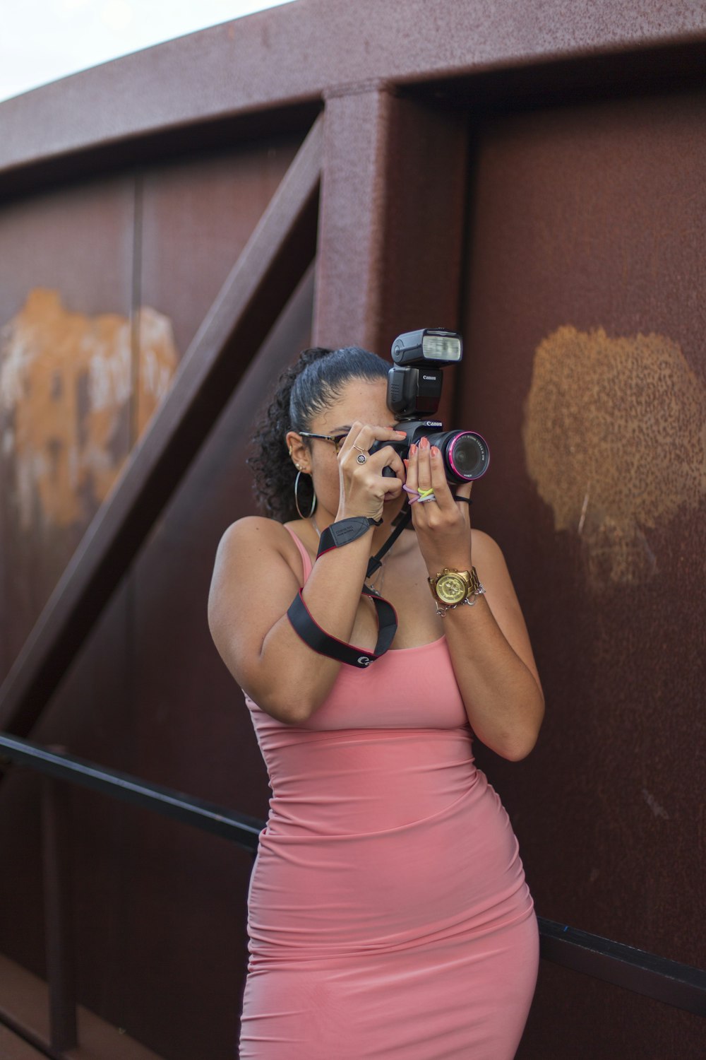 woman in pink tank top holding black dslr camera