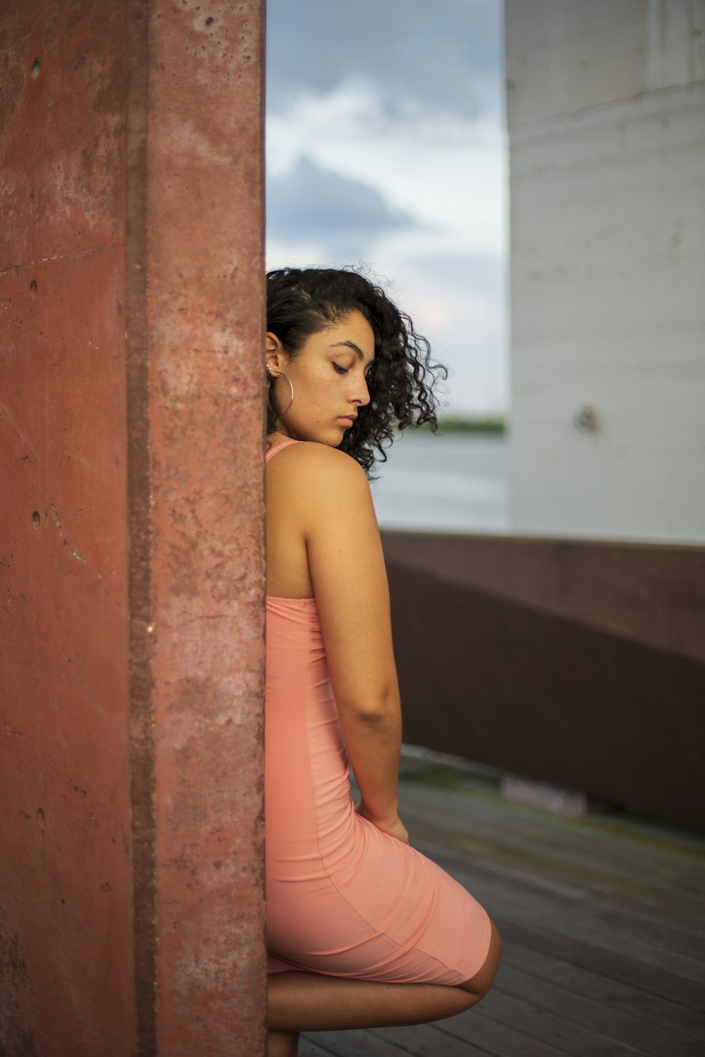 woman in pink tank top leaning on brown concrete wall during daytime