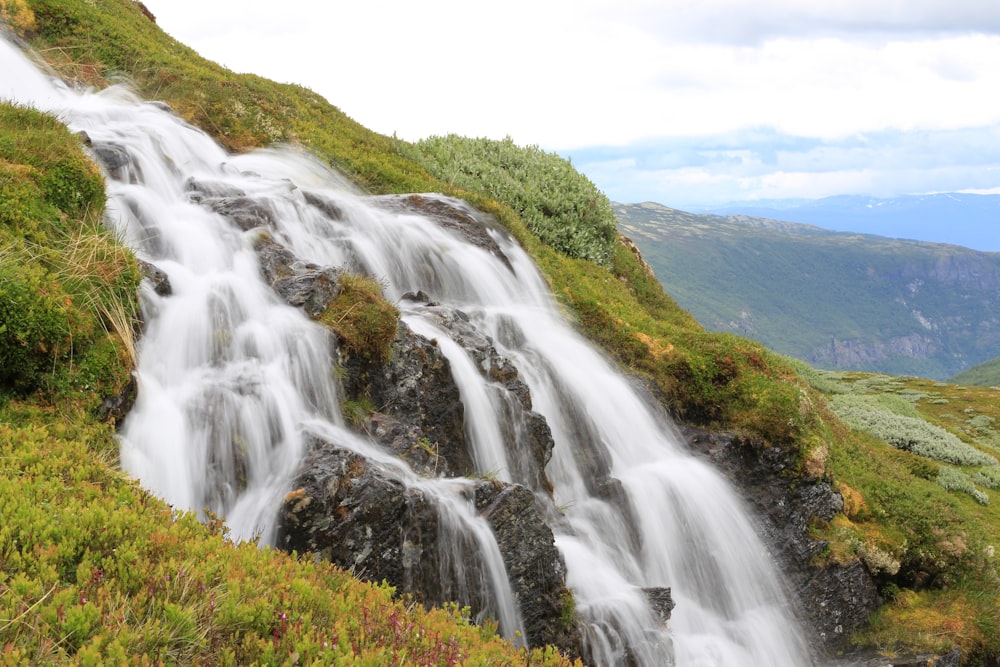 waterfalls on green grass field during daytime