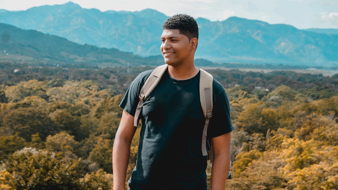 man in black and white crew neck t-shirt standing on mountain during daytime