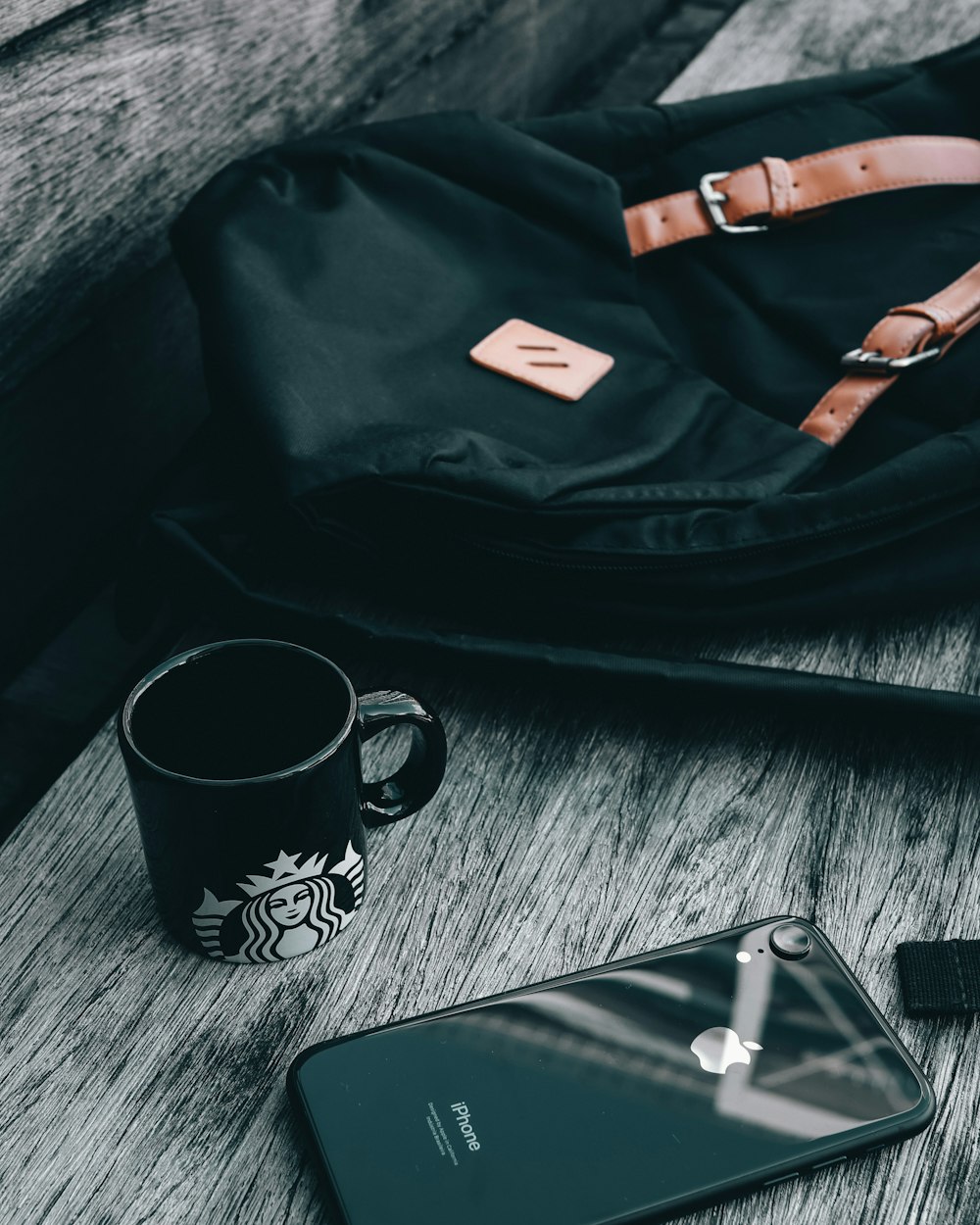 black and white ceramic mug beside black and orange leather sling bag