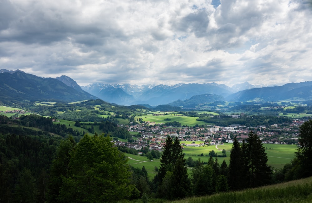 green trees and mountains under white clouds and blue sky during daytime