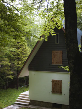 A cozy cottage nestled among tall trees with a welcoming front deck.