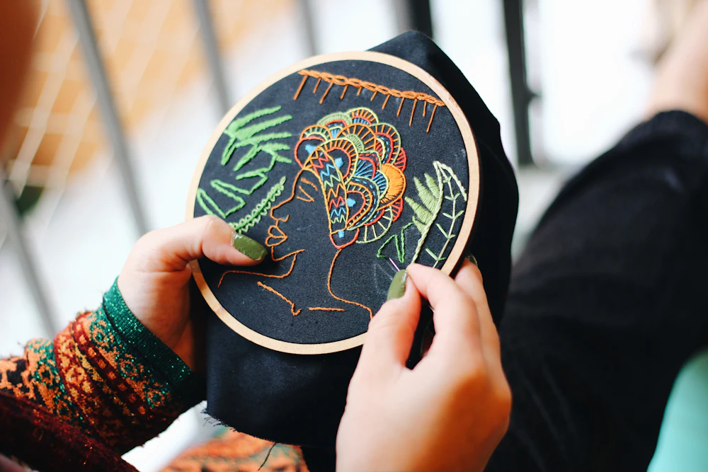 Hands holding up a finished embroidery hoop for inspection