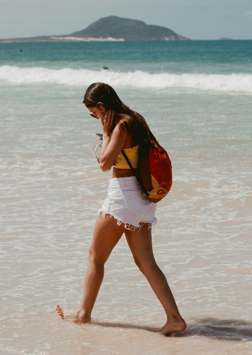 woman in white shorts standing on beach during daytime