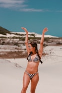 woman in black and white bikini standing on white sand during daytime