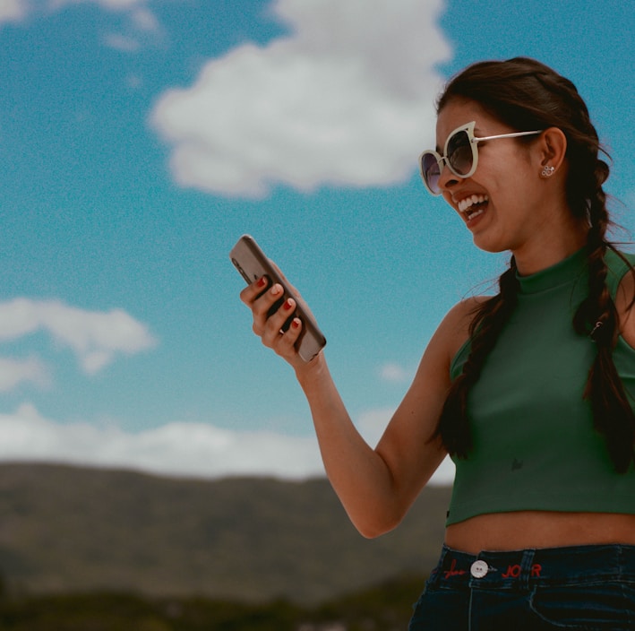 woman in green tank top holding smartphone during daytime