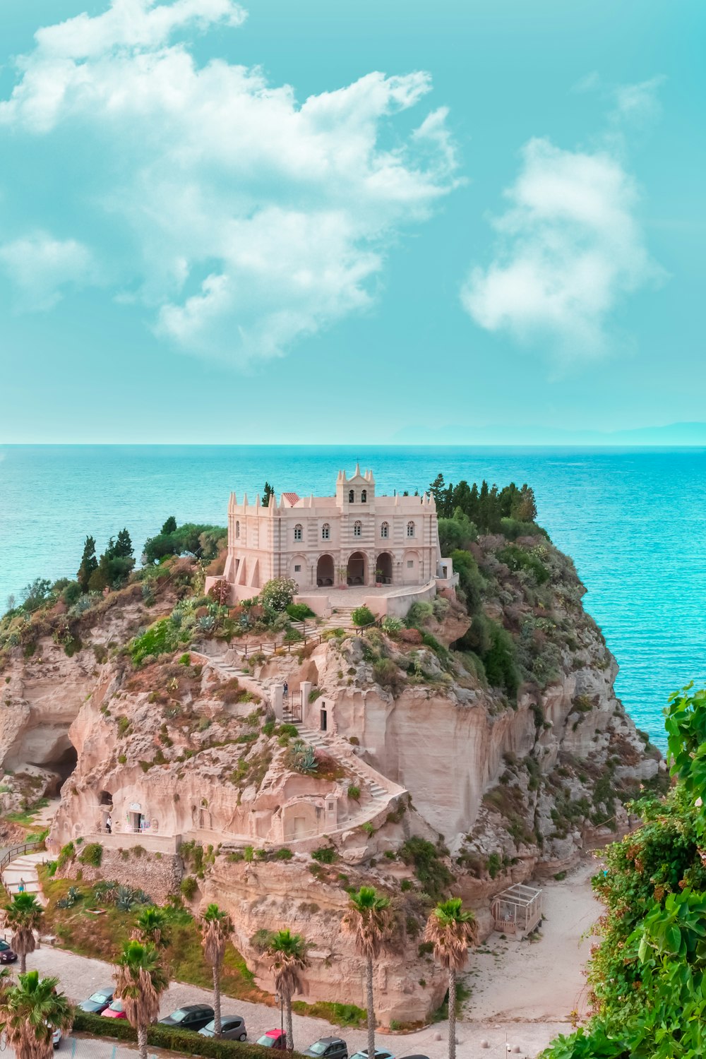 Edificio in cemento marrone sulla scogliera in riva al mare sotto il cielo blu durante il giorno