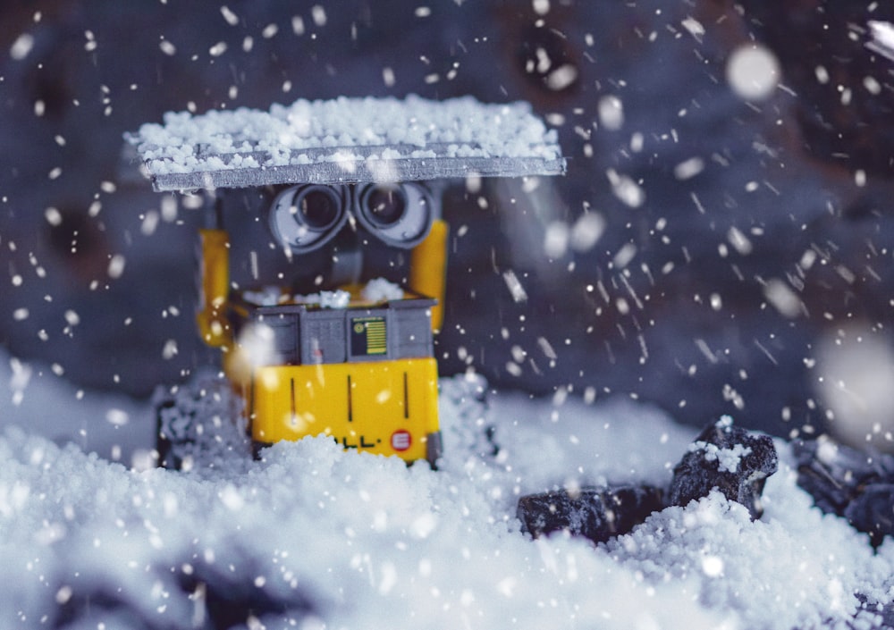 Camión de juguete de plástico amarillo y negro en suelo cubierto de nieve