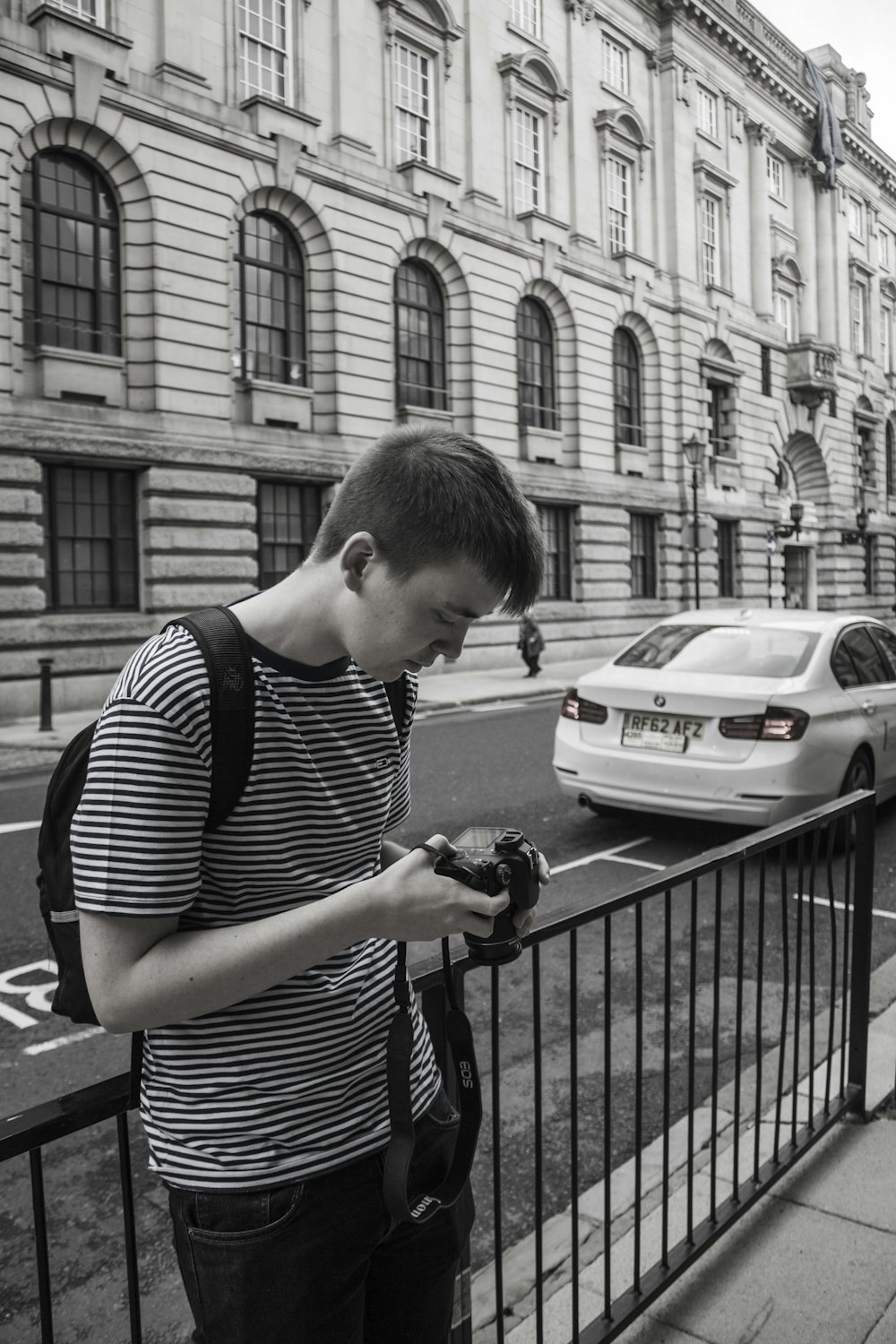 man in black and white stripe t-shirt holding black dslr camera