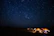 A serene Bhutanese mountain village under a vast, starlit sky showcasing shimmering constellations.