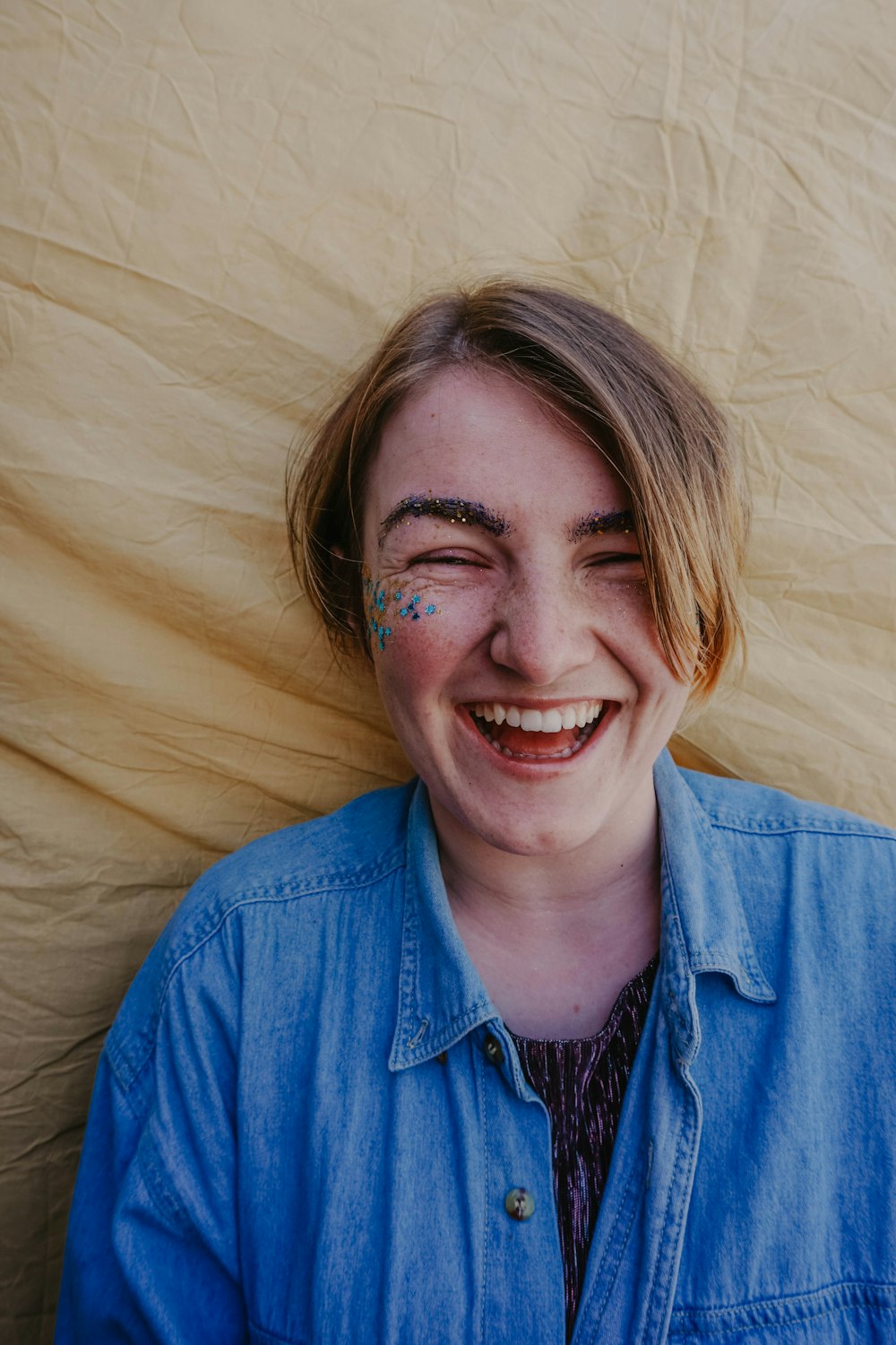 woman in blue button up shirt lying on brown textile