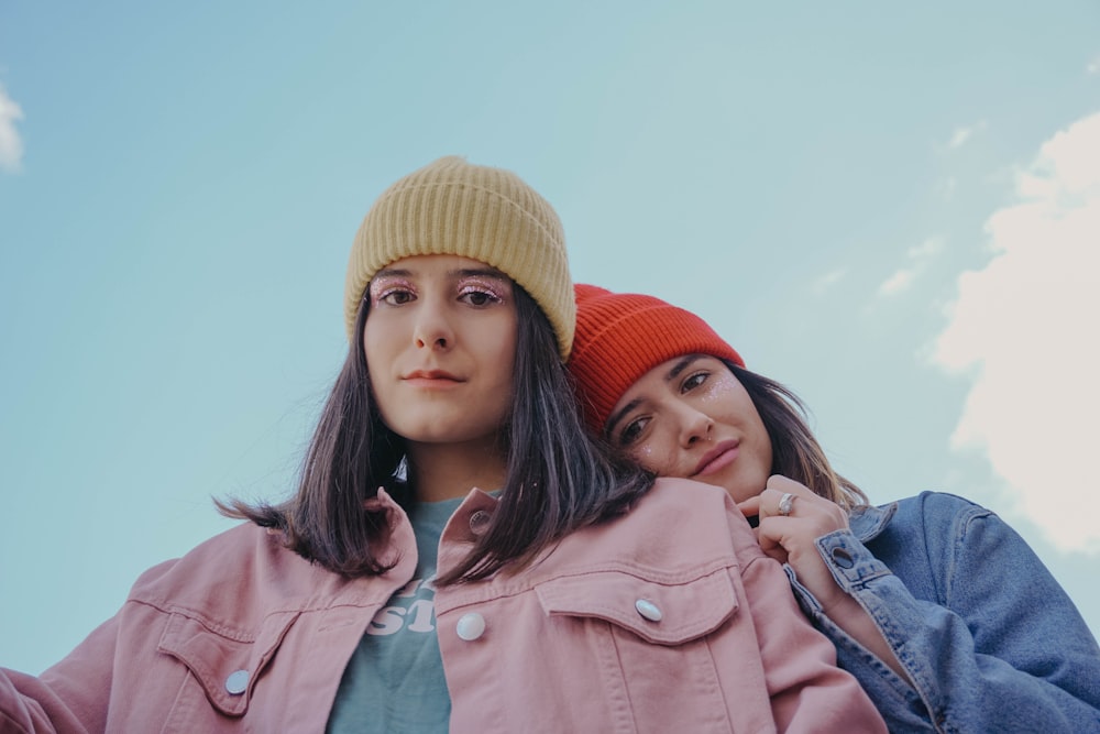 woman in blue denim jacket beside woman in orange knit cap