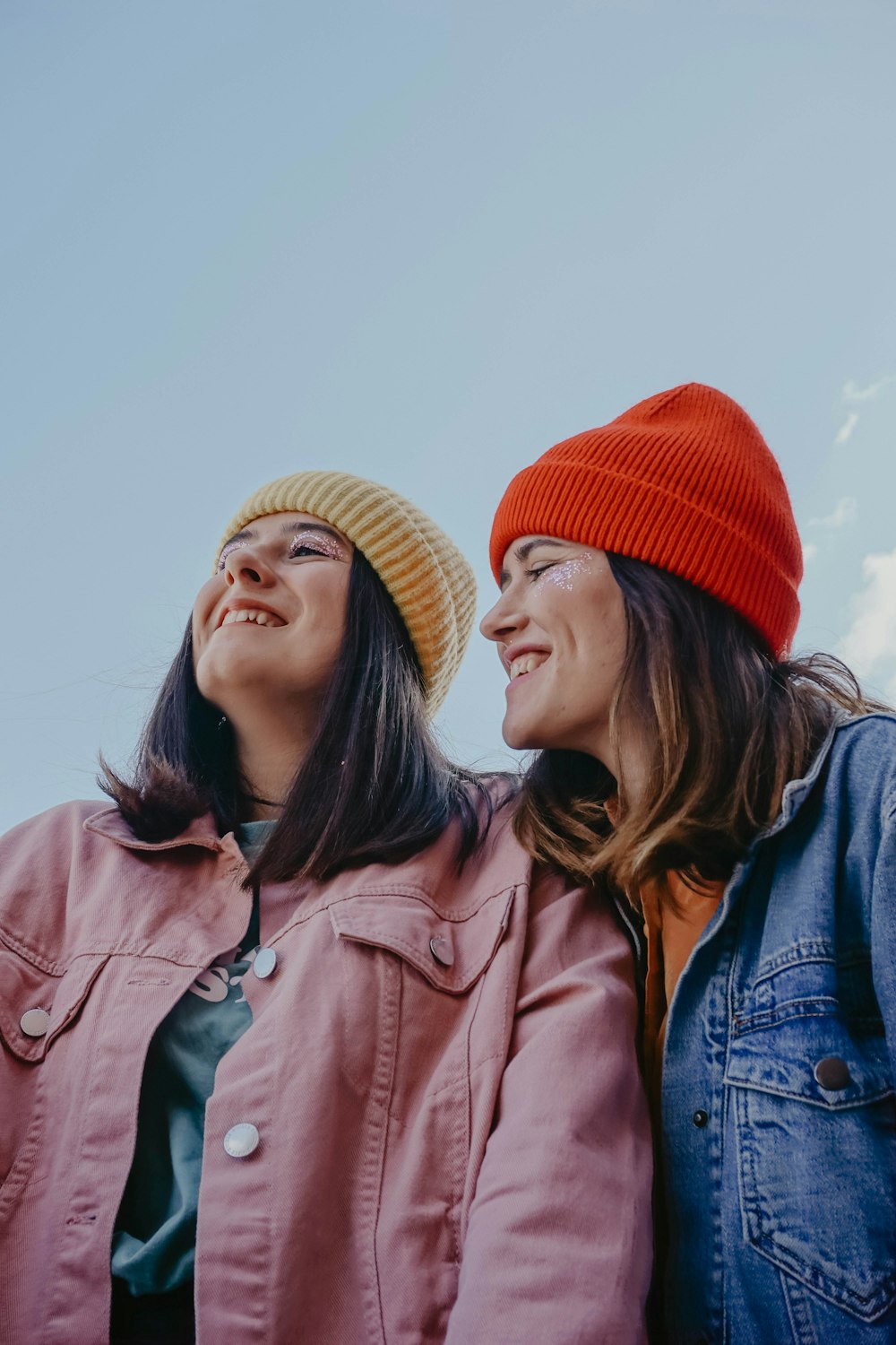 2 women wearing red knit cap and blue denim jacket