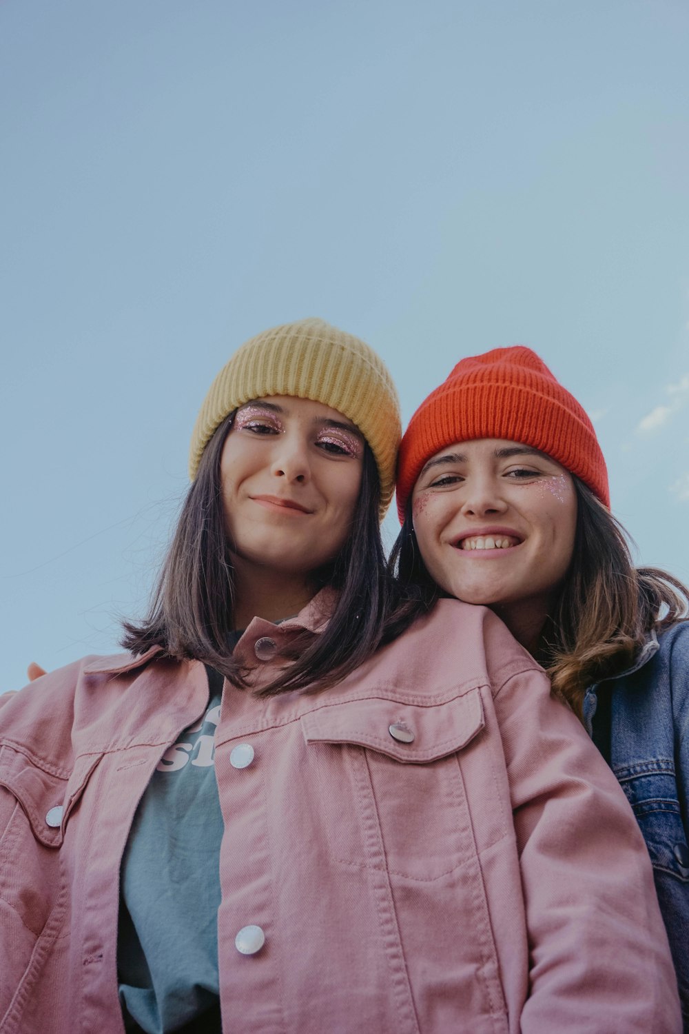 2 women smiling wearing red knit cap