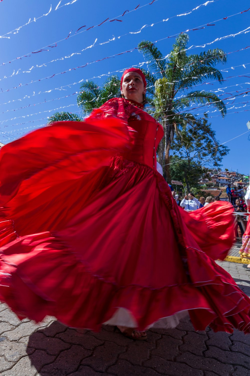 woman in red dress standing near green tree during daytime