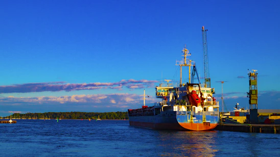 A sleek cargo ship docked at a modern port under a clear sky, symbolizing smooth global trade.