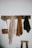 Close-up of a rustic wall-mounted coat rack with leather straps holding scarves and bags.