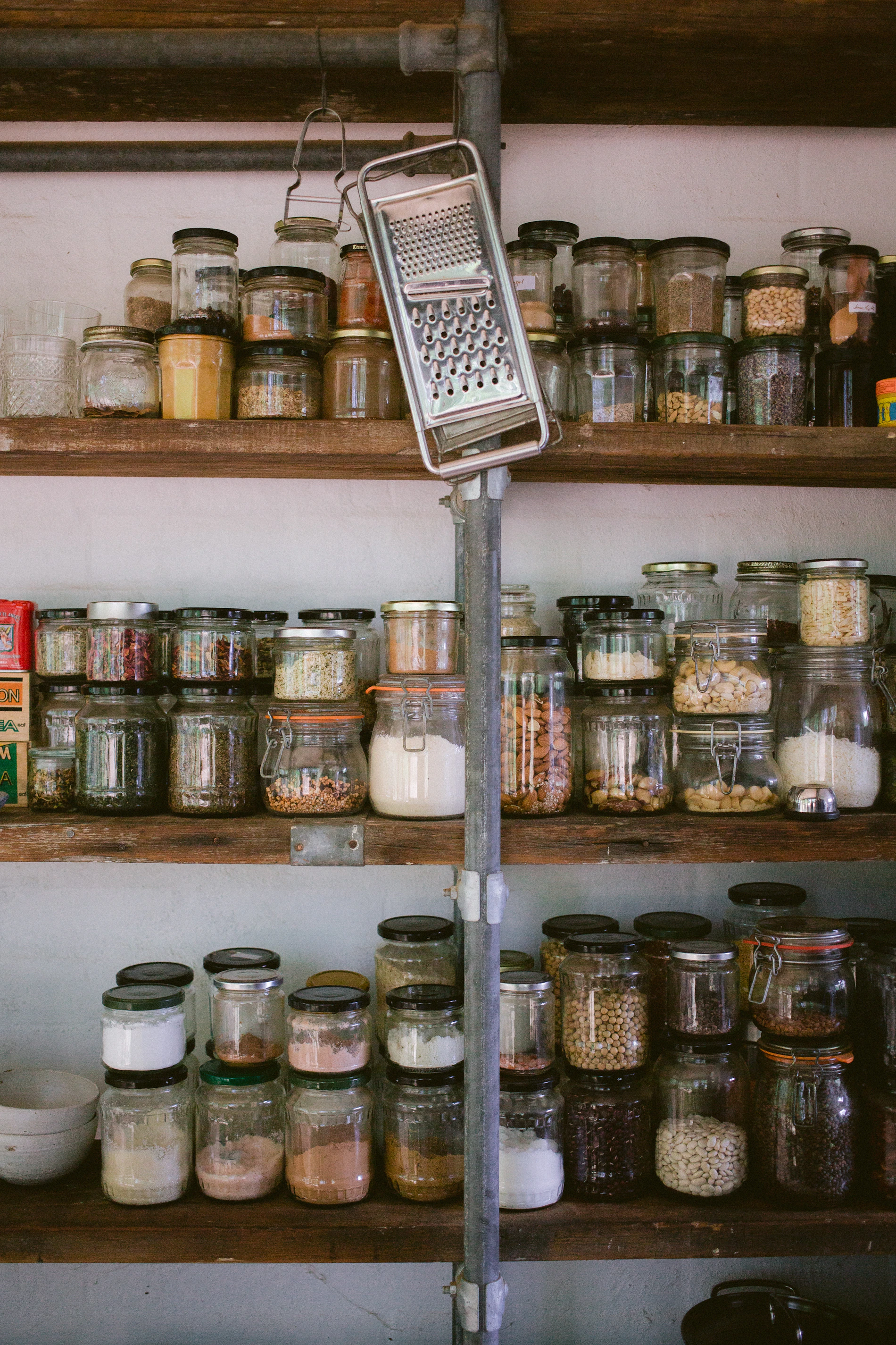 Glass jars with dry pantry ingredients arranged on open kitchen shelving