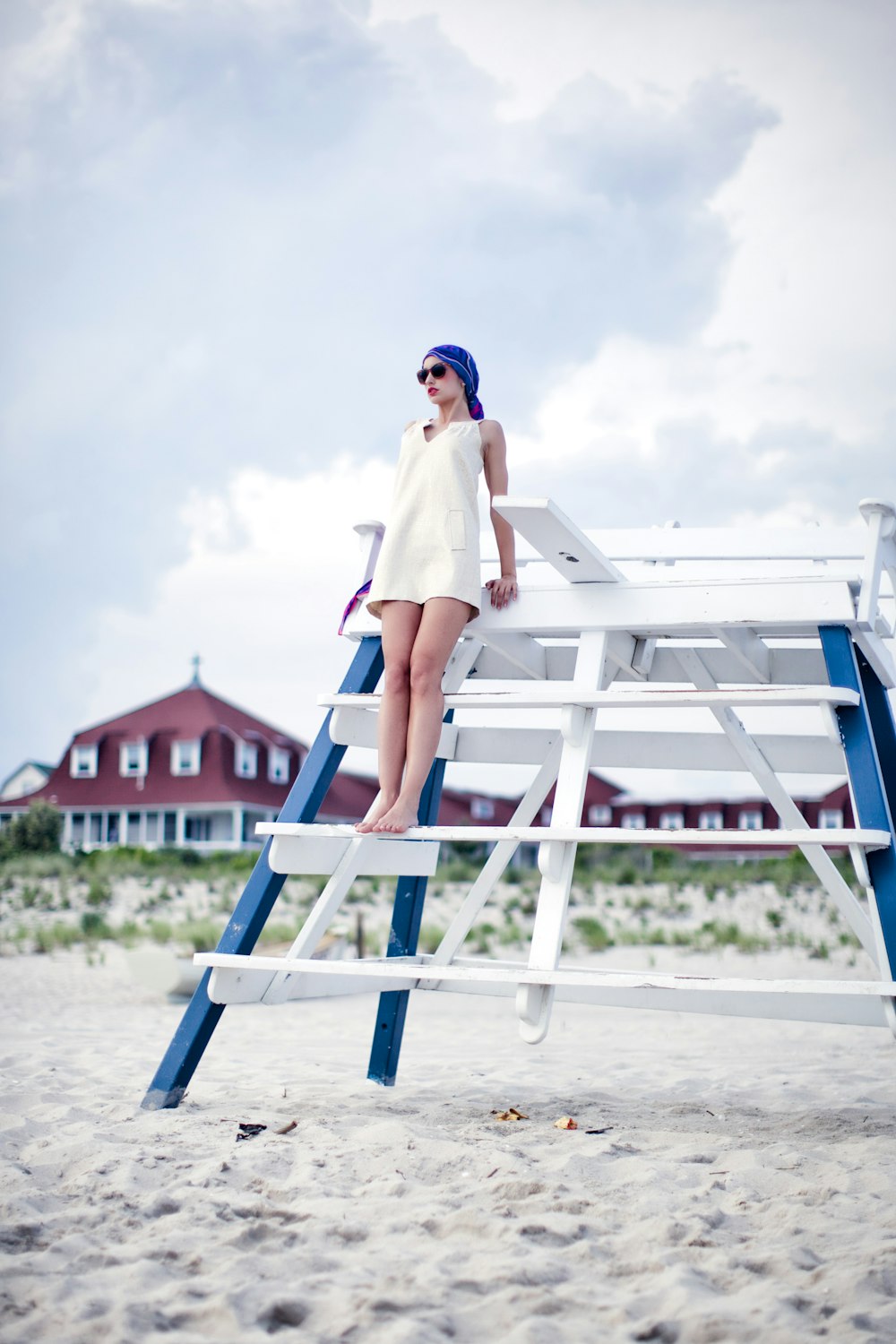 woman in white dress sitting on blue and white wooden chair on beach during daytime