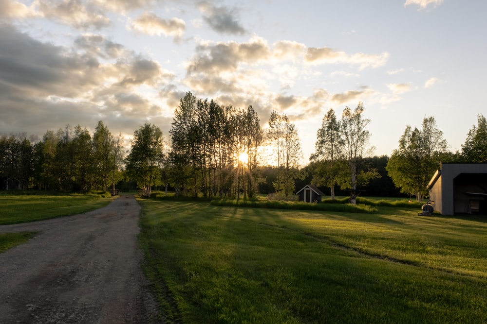 green grass field near trees under cloudy sky during daytime