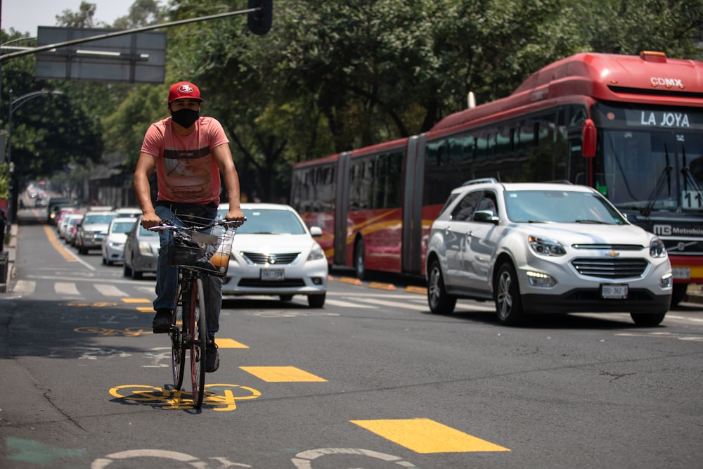 man in red t-shirt riding bicycle on road during daytime