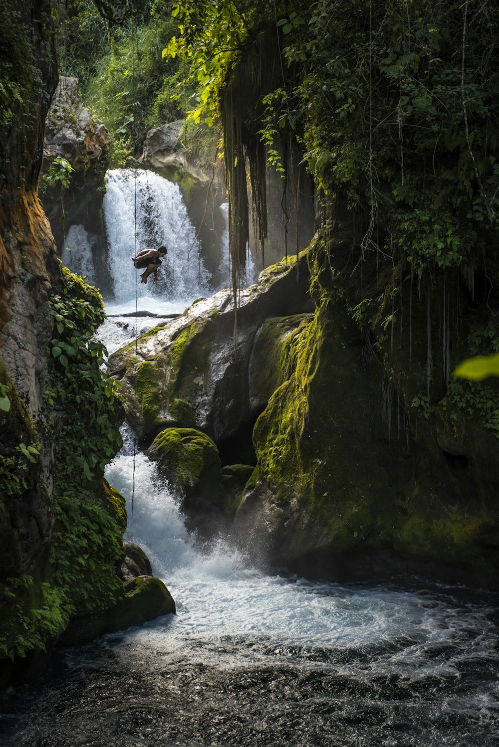 water falls in the middle of green moss covered rocks