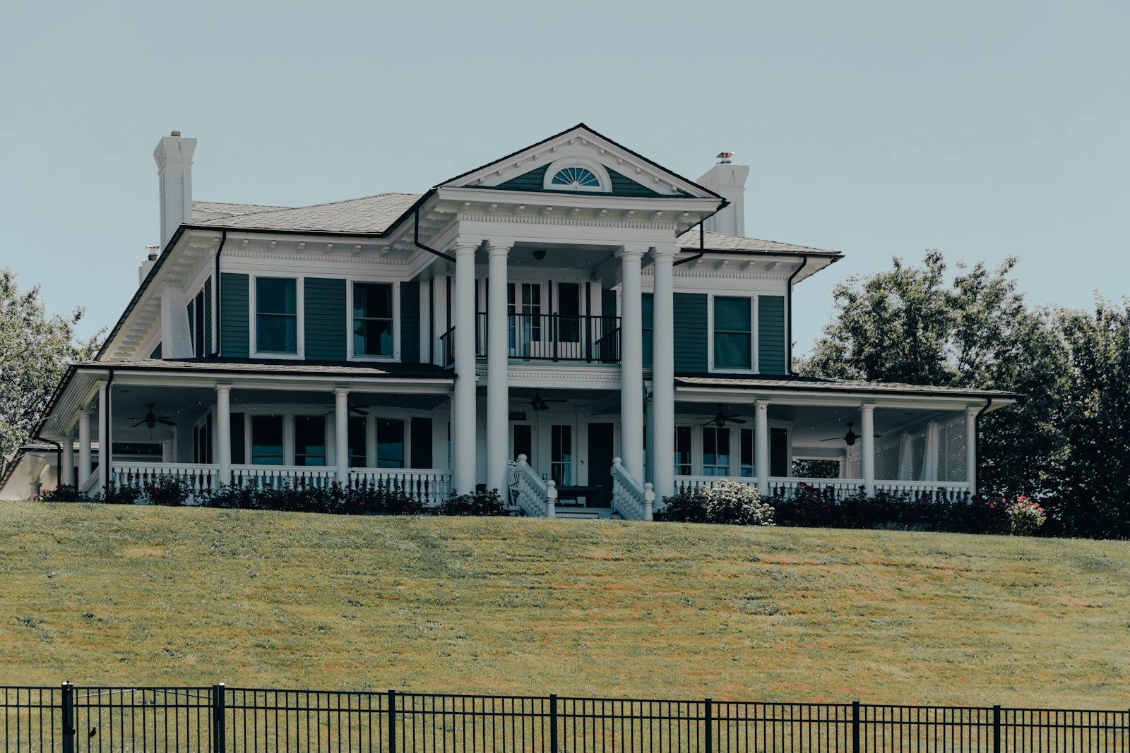 A white columned house behind a clipped lawn.