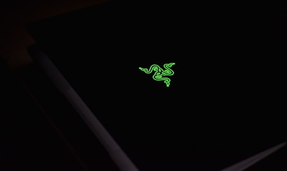 A dark surface with a vibrant green logo resembling three stylized snakes intertwined, illuminating against the black background.