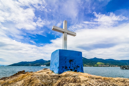 blue cross on brown rock under blue sky during daytime in São Sebastião Brasil